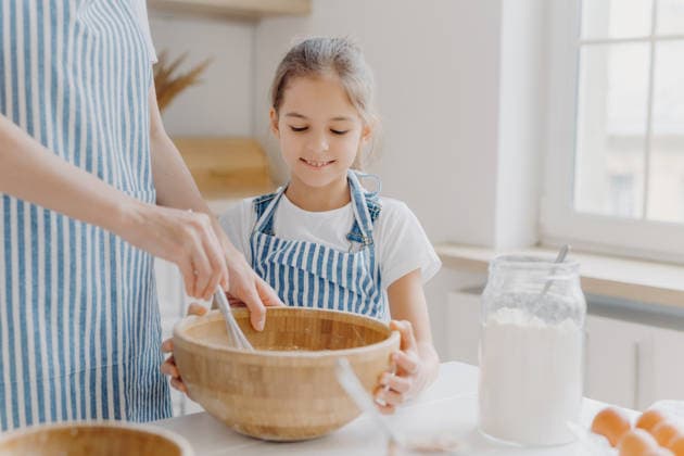 Ein kleines Mädchen verrührt Zutaten in einer Holzschüssel, während es zu Hause in der Küche mit seiner Mutter backt Little girl whisks ingredients in wooden bowl while baking with mother in kitchen at home (License=RF) ,model released, Symbolfoto Copyright: xZoonar.com ViorelxKurnosovx 25184569 ,model released, Symbolfoto ,property released