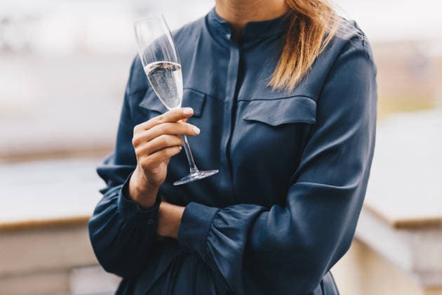 Eine Frau in einer marineblauen Bluse hält während der Feier auf der Dachterrasse ein Glas Champagner in der Hand Woman in navy blue blouse holds glass of champagne outdoors on rooftop terrace during celebration (License=RF) ,model released, Symbolfoto Copyright: xZoonar.com ViorelxKurnosovx 25184573 ,model released, Symbolfoto ,property released