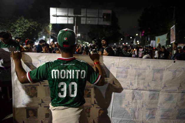 Mexico City Missing Persons March A demonstrator in a Mexico football shirt holds a large banner showing missing-person search notices during a demonstration on Calzada de Tlalpan in Mexico City, Mexico, on June 10, 2026. The march, heading toward Estadio Azteca as part of the Let s illuminate the search event, brought together families from various Mexican states calling for justice for their missing relatives. Mexico City Mexico City Mexico Copyright: xXavierxDuartex
