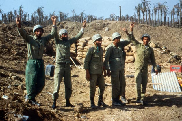 Fünf iranische Kämpfer in Uniform stehen vor Sandsäcken in einer unwegsamen Landschaft mit zerstörten Palmen im Hintergrund. Einige der Soldaten tragen Helme und strecken ihre Arme mit dem Victory-Zeichen in die Höhe. Iran, 1981 Teheran Iran *** five Iranian Fighters in Uniform Standing before Sandbags in a impassable Landscape with destroyed Palm trees at Background some the Soldiers carry Helmets and stretch their Arms with the Victory Character in the Height Iran, 1981 Tehran Iran Copyright: xUnitedxArchivesx xSvenxSimonxArchives SVS_94010005062