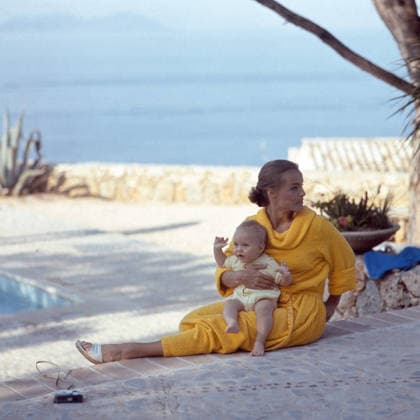 Die Schauspielerin Romy Schneider sitzt in einem gelben Bademantel am Pool und hält ihren kleinen Sohn David auf dem Schoß. Im Hintergrund ist das Meer zu sehen. 1967 - *** the Actress Romy Schneider sits in a yellow Bathrobe on Pool and holds their small Son David at the Lap at Background is the Sea to see 1967 Copyright: xUnitedxArchivesx xSvenxSimonxArchives SVS_94040000615