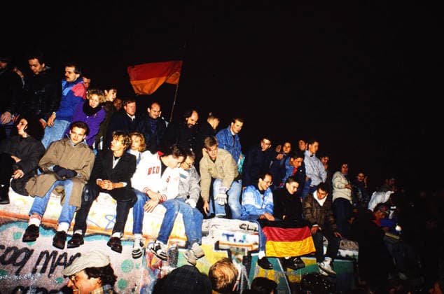 Boy People sit at night at the Berlin Wall on Potsdam Place, some hold German flags, the Wall is with Graffiti painted, Germany, 1989 Berlin Berlin Germany Copyright: xUnitedxArchivesx xSvenxSimonxArchive