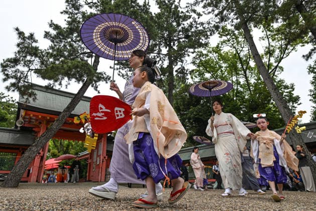 Osaka Keeps Centuries Old Otaue Rice Festival alive OSAKA, JAPAN - JUNE 14: Young children participating as sacred chigo walk in a ceremonial procession alongside women holding traditional purple paper umbrellas (wagasa) during the historic Otaue Rice Planting Festival (Otaue Shinji) at Sumiyoshi Taisha Shrine in southern Osaka, Japan, on June 14, 2026. The ancient agricultural ritual, officially designated as an Important Intangible Folk Cultural Property of Japan, includes chigo children dressed in traditional robes, face paint, and elaborate hairstyles to represent purity as they walk the shrine grounds to pray for a bountiful harvest. Artur Widak Anadolu Agency Anadolu Osaka Japan. Editorial use only. Please get in touch for any o  Copyright: x2026xAnadoluxArturxWidak AnadoluxAgencyx