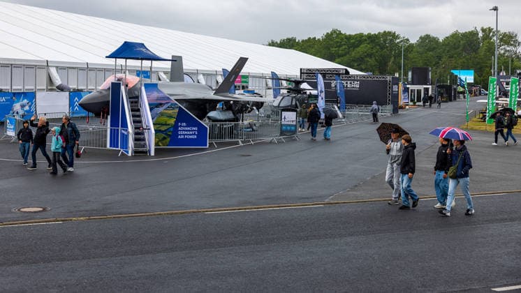 Publikumstag auf ILA Berlin 2026, Berlin, 14.06.2026 Besucher gehen bei wechselhaftem Wetter ueber das Aussengelaende der ILA Berlin. Am Stand ist ein Lockheed Martin F-35 Kampfjet ausgestellt, Mehrere Besucher schuetzen sich mit Regenschirmen vor dem Regen. Schöneberg Berlin ExpoCenter Airport Brandenburg Deutschland *** Public day at ILA Berlin 2026, Berlin, 14 06 2026 Visitors walk through the outdoor area of the ILA Berlin in changeable weather A Lockheed Martin F 35 fighter jet is on display at the stand, Several visitors protect themselves from the rain with umbrellas Schöneberg Berlin ExpoCenter Airport Brandenburg Germany 20260614-286A0192-M4000