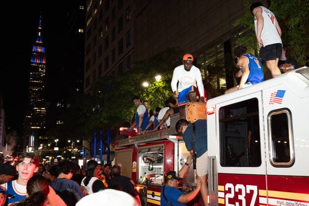 June 14, 2026, New York, New York, USA: Fans of the New York Knicks climb atop an FDNY fire engine with the Empire State building, lit blue and orange, in the background. New York USA - ZUMAf193 20260614_znp_f193_009 Copyright: xDerekxFrenchx