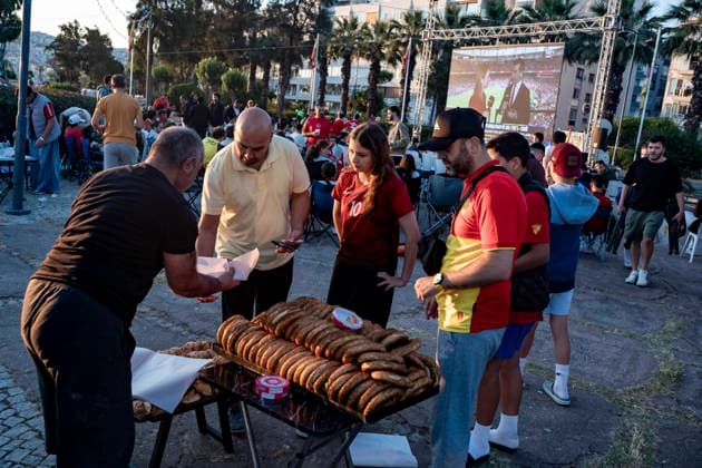 Turkish Fans Gather for the Match People collect simit from a vendor as Turkish fans gather to watch the FIFA World Cup Group D match between Turkey and Australia on a giant screen in the Konak district of Izmir, Turkey, on June 14, 2026. This marks Turkey s first appearance in the FIFA World Cup finals since the 2002 tournament. Turkey finished third at the 2002 FIFA World Cup. Izmir Izmir Turkey Copyright: xMuratxKocabasx