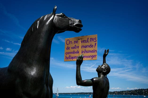 Demonstration against the G7 summit in Geneva on June 14, 2026 Nicolas Liponne MAXPPP Geneve 14 06 2026 A statue of a horse and a man holding a sign that reads We dont want your cannibalistic, inhumane, bellicose, deceitful world, during the international demonstration against fascism, capitalism and imperialism, as part of the mobilization of the G7 counter summit, qui aura lieu à Évian du 15 au 17 juin, à Genève le 14 juin 2026 A statue of a horse and a man holding a sign that reads We dont want your cannibalistic, inhumane, bellicose, deceitful world, at the international demonstration against fascism, capitalism, and imperialism, as part of the mobilization for the G7 counter summit, which will take place in Évian from June 15 to 17, i  Copyright: xMAXPPPxNicolasxLiponnex NLP202606152275 NLP202606152275