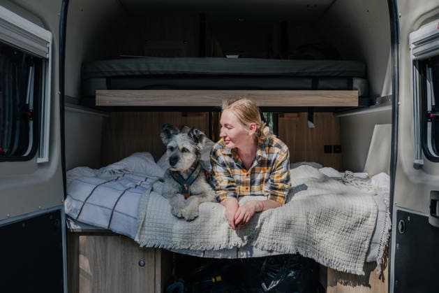 Woman and her dog relaxing in camper van bed Inari, Lapland, Finland CR_PJJZ260615-2052061-01 ,model released, Symbolfoto