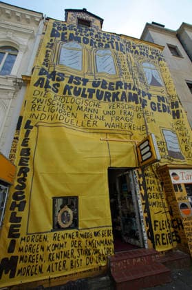 Der Buchladen Golden Shop im Bremer Steintorviertel hat im Juni 2026 seine gelbe, mit schwarzen Sprüchen bemalte Fassade mit einem Transparent verhüllt, das in derselben Gestaltung angebliche Zitate von Kulturstaatsminister Wolfram Weimer wiedergibt. Damit reagiert die linke Buchhandlung auf die Entscheidung des konservativen Politikers, ihr nicht den Deutschen Buchhandlungspreis zu verleihen, obwohl eine Jury die Buchhandlung dafür auserwählt hatte. Als Begründung erwähnte er nicht näher erläuterte Erkenntnisse des Verfassungsschutzes. Auf dem Transparent steht auch eine Strophe aus einem Gedichtband namens Kopfpilz, den Weimer als junger Mann 1986 im Eigenverlag veröffentlichte: Morgen, Rentner, wirds was geben. Morgen kommt der