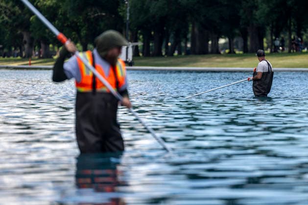 U.S. National Park Service employees use a vacuum pump to clean algae off the bottom of the newly repainted Lincoln Memorial Reflecting Pool on the National Mall in Washington, DC on Wednesday, June 17, 2026. The Trump Administration spent $16 million to paint the bottom of the pool American flag blue and as part of an effort to repair Washington landmarks in for preparation the country s 250th birthday this summer.  WAP20260617313 BONNIExCASH
