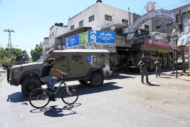 Palestinian-Israeli conflict in Nablus, Palestine - 18 Jun 2026 A Palestinian rides his bicycle past soldiers stationed at the entrance to the market during a raid on Balata refugee camp, east of Nablus in the West Bank. Israeli forces raided the central market during a security operation. Palestinian sources said that the army arrested seven Palestinians from various neighborhoods in Nablus and its surrounding refugee camps. Nablus Palestine Copyright: xNasserxishatyehx xSOPAxImagesx Nishtayeh2329