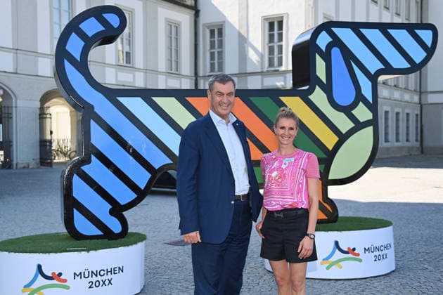 News Bilder des Tages Markus SOEDER (Ministerpraesident Bayern und CSU Vorsitzender), Jessica BREDOW WERNDL vor dem Maskottchen,Olympia Dackel. Pressetermin im Rahmen der Einladung der Olympischen Spitzenverbaende zur Vorstellung des vertieften Bewerbungskonzepts Muenchen 20XX am Donnerstag, 18.06.2026 vor dem Schloss Nymphenburg *** Markus SOEDER, Minister-President of Bavaria and CSU Chairman, Jessica BREDOW WERNDL in front of the mascot, Olympia the Dachshund, at a press event held as part of the invitation extended by the leading Olympic federations to present the detailed bid concept for Munich 20XX on Thursday, June 18, 2026, in front of Nymphenburg Palace,detected_source_language