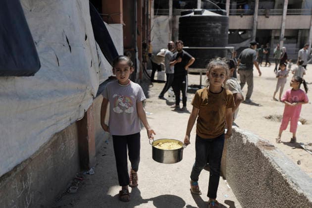 Jabalia Gaza Strip Displacement Crisis Displaced Palestinian girls carry a pot of food aid at the Al-Faluja School shelter in Jabalia, in the northern Gaza Strip, on June 18, 2026. Thousands of displaced families in northern Gaza rely on humanitarian assistance as shortages of food, water and basic supplies persist amid the continuing conflict and humanitarian crisis. Gaza Gaza Strip Palestinian Territories Copyright: xAhmedxAlxArinix