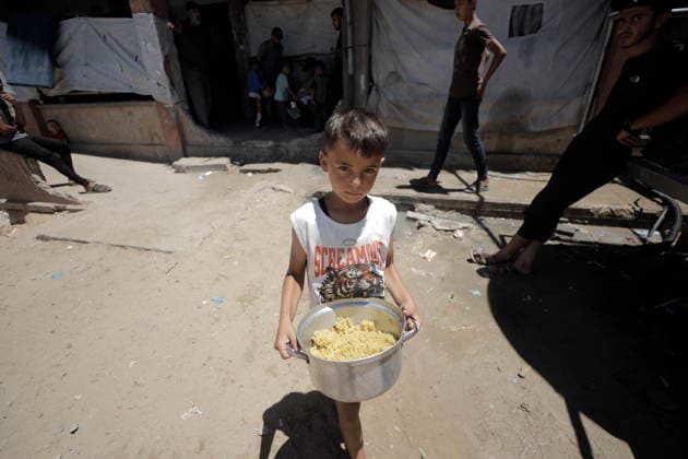 Jabalia Gaza Strip Displacement Crisis A displaced Palestinian boy carries a pot of food aid at the Al-Faluja School shelter in Jabalia, in the northern Gaza Strip, on June 18, 2026. Thousands of displaced families in northern Gaza rely on humanitarian assistance as shortages of food, water and basic supplies persist amid the continuing conflict and humanitarian crisis. Gaza Gaza Strip Palestinian Territories Copyright: xAhmedxAlxArinix