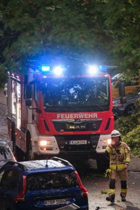 Ein Löschfahrzeug der Feuerwehr Köln mit eingeschaltetem Blaulicht im nächtlichen Dauereinsatz in Köln-Nippes; Einsatzkräfte beseitigen nach einem schweren Unwetter mit Sturmböen und Gewittern umgestürzte Bäume und blockierte Straßen im Kölner Stadtgebiet. *** A Cologne fire department truck with flashing blue lights during a continuous emergency operation in Cologne-Nippes; firefighters clearing fallen trees and blocked roads after a severe storm with heavy thunderstorms and gales. Nordrhein-Westfalen Deutschland, Germany DSCF6992