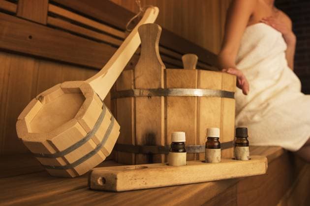 Badzubehör aus Holz mit Aromaölflasche für das Bad in der Sauna und Frau im Hintergrund Wooden bath accessories with aromatic oil bottle for bath in the sauna and woman on background Copyright: imageBROKER RuslanxOlinchuk ibxiqx17617186.jpg
