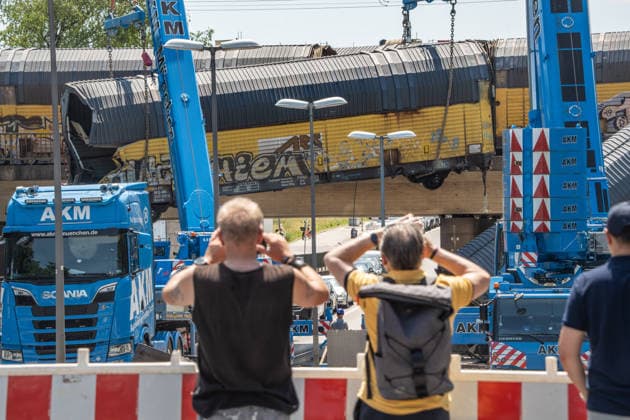 Schweres Güterzug-Unglück in München, Bergung eines Waggons, der von der Brücke gestürzt ist, Samstagmittag, München, 20.. Juni 2026 Deutschland, München, 20. Juni 2026, schweres Güterzug-Unglück in München, ein Toter, zwei Kräne bergen einen Waggon, der in der Nacht von der Brücke gestürzt ist, Schaulustige verfolgen die Bergungsarbeiten am Samstagmittag, das Zugunglück hatte sich nachts um 1:40 Uhr ereignet, zwei Güterzüge stießen beim Rangieren zusammen, Waggons stürzten von der Brücke, ein Mensch wurde tödlich verletzt, die Schleißheimer Straße, ist in diesem Bereich gesperrt, Milbertshofen, Verkehr, Bahn, Bayern, *** Serious freight train accident in Munich; recovery of a railcar that fell off a bridge; Saturday a