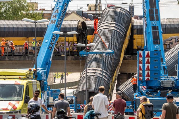 Schweres Güterzug-Unglück in München, Bergung eines Waggons, der von der Brücke gestürzt ist, Samstagmittag, München, 20.. Juni 2026 Deutschland, München, 20. Juni 2026, schweres Güterzug-Unglück in München, ein Toter, zwei Kräne bergen einen Waggon, der in der Nacht von der Brücke gestürzt ist, Schaulustige verfolgen die Bergungsarbeiten am Samstagmittag, das Zugunglück hatte sich nachts um 1:40 Uhr ereignet, zwei Güterzüge stießen beim Rangieren zusammen, Waggons stürzten von der Brücke, ein Mensch wurde tödlich verletzt, die Schleißheimer Straße, ist in diesem Bereich gesperrt, Milbertshofen, Verkehr, Bahn, Bayern, *** Serious freight train accident in Munich; recovery of a railcar that fell off a bridge; Saturday a