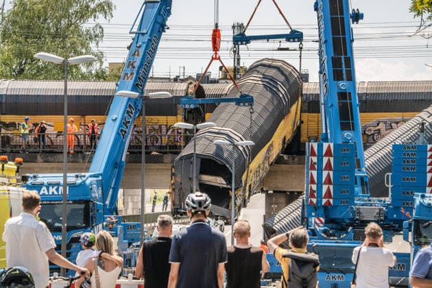 Schweres Güterzug-Unglück in München, Bergung eines Waggons, der von der Brücke gestürzt ist, Samstagmittag, München, 20.. Juni 2026 Deutschland, München, 20. Juni 2026, schweres Güterzug-Unglück in München, ein Toter, zwei Kräne bergen einen Waggon, der in der Nacht von der Brücke gestürzt ist, Schaulustige verfolgen die Bergungsarbeiten am Samstagmittag, das Zugunglück hatte sich nachts um 1:40 Uhr ereignet, zwei Güterzüge stießen beim Rangieren zusammen, Waggons stürzten von der Brücke, ein Mensch wurde tödlich verletzt, die Schleißheimer Straße, ist in diesem Bereich gesperrt, Milbertshofen, Verkehr, Bahn, Bayern, *** Serious freight train accident in Munich; recovery of a railcar that fell off a bridge; Saturday a