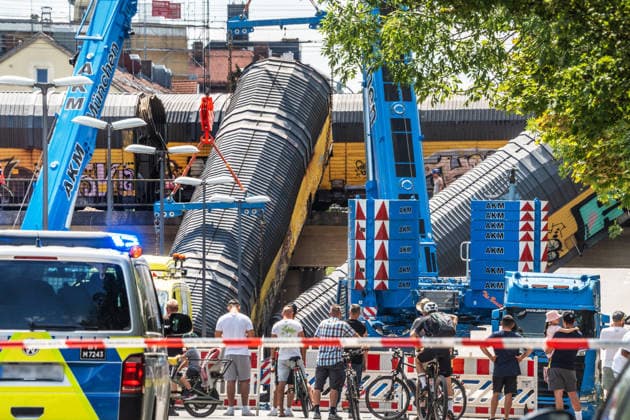 Schweres Güterzug-Unglück in München, Bergung eines Waggons, der von der Brücke gestürzt ist, Samstagmittag, München, 20.. Juni 2026 Deutschland, München, 20. Juni 2026, schweres Güterzug-Unglück in München, ein Toter, zwei Kräne bergen einen Waggon, der in der Nacht von der Brücke gestürzt ist, Schaulustige verfolgen die Bergungsarbeiten am Samstagmittag, das Zugunglück hatte sich nachts um 1:40 Uhr ereignet, zwei Güterzüge stießen beim Rangieren zusammen, Waggons stürzten von der Brücke, ein Mensch wurde tödlich verletzt, die Schleißheimer Straße, ist in diesem Bereich von der Polizei gesperrt, Milbertshofen, Verkehr, Bahn, Bayern, *** Serious freight train accident in Munich; recovery of a railcar that fell off a br
