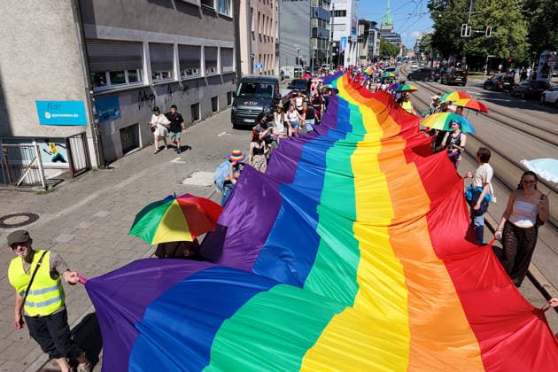 Teilnehmende tragen beim Christopher Street Day (CSD) in Ulm und Neu-Ulm eine ueber 100 Meter lange und 4,2 Meter breite Regenbogenfahne (Foto vom 20.06.2026). Die Veranstalter bezeichnen sie als die groesste Regenbogenfahne Deutschlands. Der CSD steht in diesem Jahr unter dem Motto Von Ufer zu Ufer: Wir halten zusammen! und findet zum 15. Mal statt. EDITORIAL USE ONLY *** Participants at Christopher Street Day (CSD) in Ulm and Neu Ulm are carrying a rainbow flag over 100 meters long and 4.2-meter-wide rainbow flag. Photo taken on June 20, 2026. The organizers describe it as Germany’s largest rainbow flag. This year’s CSD is themed From Shore to Shore Copyright: epd-bild ThomasxHeckmann 260620_Heckmann_Ulm_CSD_Regenbogenfahne_4945