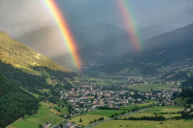 Luftaufnahme des österreichischen Kurorts Bad Hofgastein im Gasteinertal, über dem sich ein markanter Doppelregenbogen vor einer alpinen Bergkulisse erstreckt. Regenbogen im Gasteinertal *** Aerial view of the Austrian resort town of Bad Hofgastein in the Gastein Valley, with a striking double rainbow arching over it against an alpine mountain backdrop Rainbow in the Gastein Valley,detected_source_language