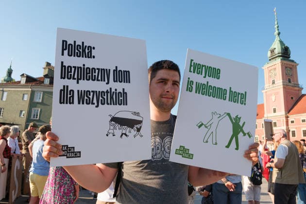 June 20, 2026, Warsaw, Masovian Voivodeship, Poland: A protester holds up placards that read Poland: a safe home for everyone and everyone is welcome here! during a demonstration on Warsaw s Castle Square for World Refugee Day. Organized under the slogan open republic, the rally was held in protest against growing xenophobia towards migrants and refugees in Poland, as well as the increasing use of anti-migrant rhetoric by Polish conservatives and far-right politicians. Warsaw Poland - ZUMAk204 20260620_zip_k204_036 Copyright: xRomanxKozielx