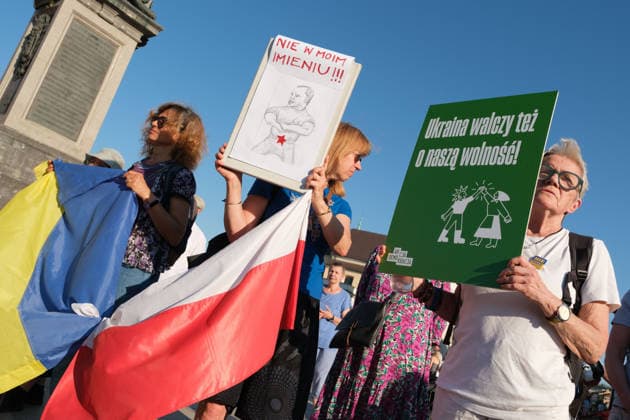 June 20, 2026, Warsaw, Masovian Voivodeship, Poland: Protesters hold a Polish and Ukrainian flag tied together during a demonstration on Warsaw s Castle Square for World Refugee Day. Organized under the slogan open republic, the rally was held in protest against growing xenophobia towards migrants and refugees in Poland, as well as the increasing use of anti-migrant rhetoric by Polish conservatives and far-right politicians. The protester on the center holds up a placard with a caricature of Polish President Karol Nawrocki and the words not in my name! while the protester on the right holds up a placard that reads Ukraine fights also for our future! Warsaw Poland - ZUMAk204 20260620_zip_k204_039 Copyright: xRomanxKozielx