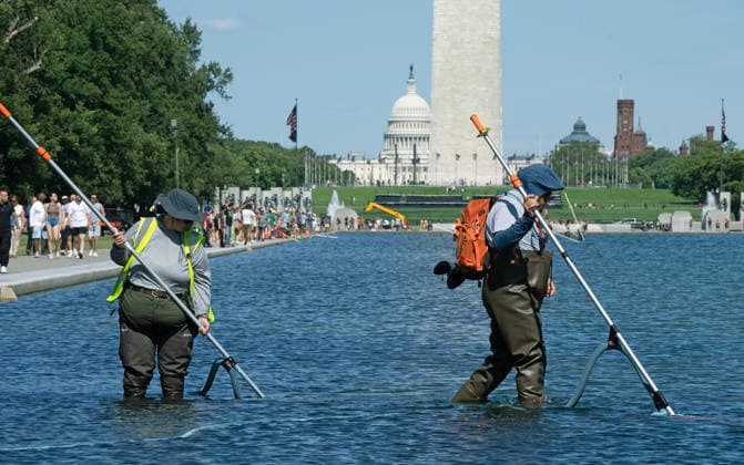 National Park Service workers use vacuum pumps to clean algae off the bottom of the newly renovated Lincoln Memorial Reflecting Pool on the National Mall in Washington, DC on Saturday, June 20,2026. The Trump Administration awarded no-bid contracts totaling nearly $15 million to renovated Reflecting Pool but it is now filled with algae and the paint is peeling. Dozens of National Guard and other police stop people from taking the blue paint chips floating in the water, with some arrests.  WAP2026062012 PATxBENIC