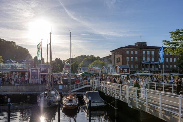 22.06.2026 Kieler Woche 2026 Eindrücke und Szenen vom Montag Abendstimmung bei den Fischbuden an der Kiellinie in Höhe Reventloubrücke. Rechts die Gebäude der Landesregierung Kiel Kiellinie Schleswig Holstein Deutschland *** June 22, 2026 Kiel Week 2026 Impressions and scenes from Monday evening at the fish stands along the Kiellinie near the Reventlou Bridge. On the right are the buildings of the state government in Kiel. Kiellinie, Schleswig-Holstein, Germany,detected_source_language