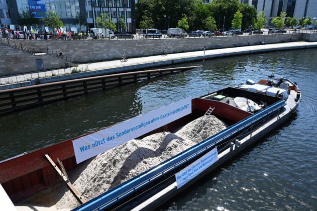 Cargo ship blocks Spree River during rally in Berlin BERLIN, GERMANY - JUNE 24: Participants gather on the banks of the Spree River as a cargo ship blocks the waterway in front of the Reichstag building during a rally organized by MIRO, the German minerals and aggregates industry association, in Berlin, Germany, on June 24, 2026. An 80-meter cargo ship loaded with construction aggregates blocked traffic on the Spree River while demonstrators called for stronger legal protection of mineral deposits and greater consideration of domestic mineral resource extraction and processing in spatial planning legislation. Volodymyr Sindieiev Anadolu Berlin Germany. Editorial use only. Please get in touch for any other usage.  Copyright: x2026xAnadoluxVolodymyrxSindieievx