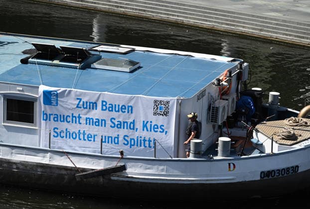Cargo ship blocks Spree River during rally in Berlin BERLIN, GERMANY - JUNE 24: A cargo ship displays a banner reading To build, you need sand, gravel, crushed stone and chippings as it blocks the Spree River in front of the Reichstag building during a demonstration organized by MIRO, the German minerals and aggregates industry association, in Berlin, Germany, on June 24, 2026. The protest called for stronger legal protection of mineral deposits and greater consideration of domestic mineral resource extraction and processing in spatial planning legislation. Volodymyr Sindieiev Anadolu Berlin Germany. Editorial use only. Please get in touch for any other usage.  Copyright: x2026xAnadoluxVolodymyrxSindieievx