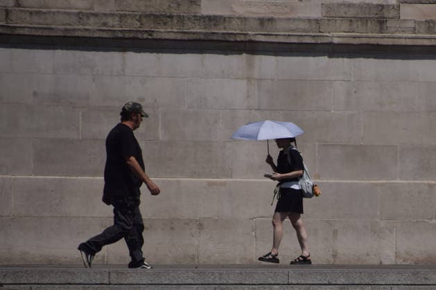 June 24, 2026, London, England, United Kingdom: A woman shelters under an umbrella from the scorching sun in Trafalgar Square as the Met Office issues an amber warning for extreme heat. London United Kingdom  - ZUMAv130 20260624_zip_v130_006 Copyright: xVukxValcicx