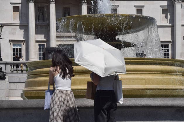 June 24, 2026, London, England, United Kingdom: Women shelter under umbrellas from the scorching sun in Trafalgar Square as the Met Office issues an amber warning for extreme heat. London United Kingdom  - ZUMAv130 20260624_zip_v130_013 Copyright: xVukxValcicx