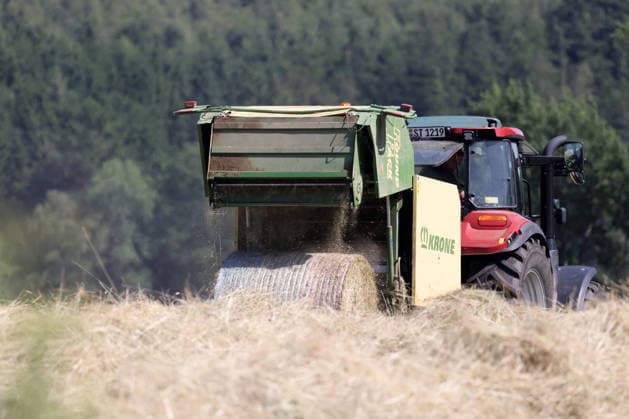 Heuernte im Siegerland. Ein Traktor mit Heuballenpresse ist bei Sonnenschein auf einer gemaehten (gemähten) Wiese bei Siegen-Oberschelden unterwegs. Sommer im Siegerland am 24.06.2026 in Siegen Deutschland. *** Hay Harvest in the Siegerland: A tractor equipped with a hay baler is driving across a mowed meadow near Siegen and Oberschelden on a sunny day. Summer in the Siegerland on June 24, 2026, in Siegen, Germany