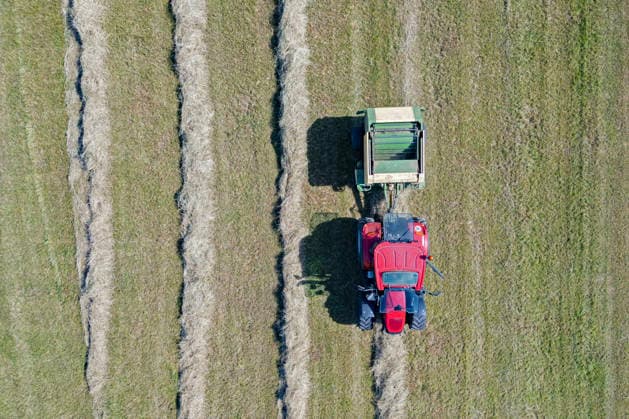 Luftaufnahme. Heuernte im Siegerland. Ein Traktor mit Heuballenpresse ist bei Sonnenschein auf einer gemaehten (gemähten) Wiese bei Siegen-Oberschelden unterwegs. Sommer im Siegerland am 24.06.2026 in Siegen Deutschland. *** Aerial view of hay harvest in the Siegerland region. A tractor equipped with a hay baler is driving across a mowed meadow near Siegen and Oberschelden on a sunny day. Summer in the Siegerland region on June 24, 2026, in Siegen, Germany.