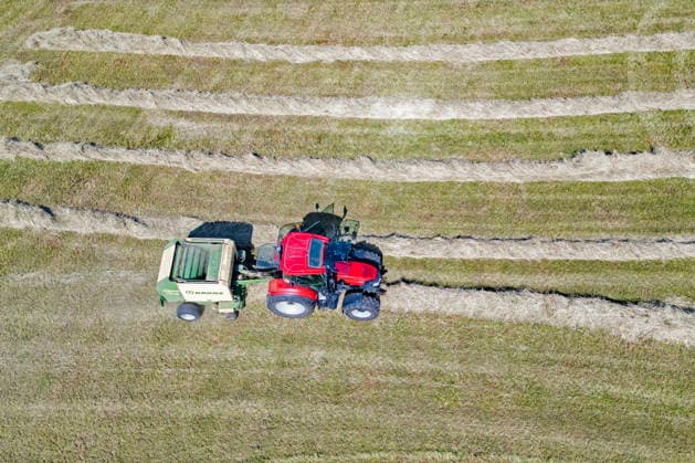 Luftaufnahme. Heuernte im Siegerland. Ein Traktor mit Heuballenpresse ist bei Sonnenschein auf einer gemaehten (gemähten) Wiese bei Siegen-Oberschelden unterwegs. Sommer im Siegerland am 24.06.2026 in Siegen Deutschland. *** Aerial view of hay harvest in the Siegerland region. A tractor equipped with a hay baler is driving across a mowed meadow near Siegen and Oberschelden on a sunny day. Summer in the Siegerland region on June 24, 2026, in Siegen, Germany.