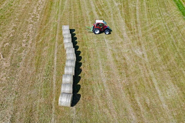 Heuernte im Siegerland. Ein Traktor legt gepresste Heuballen auf einer gemaehten (gemähten) Wiese zusammen. Sommer im Siegerland am 24.06.2026 in Siegen Deutschland. *** Hay Harvest in the Siegerland: A tractor stacks compressed hay bales on a mowed meadow. Summer in the Siegerland on June 24, 2026, in Siegen, Germany