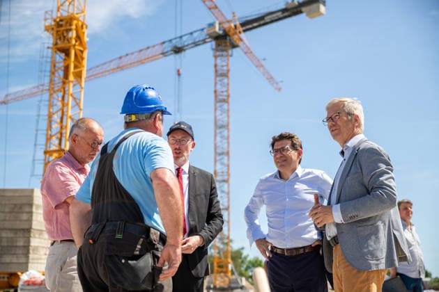Minister für Inneres und Bau Christian Pegel (3.v.l.), Nicolas Gibert-Morin (Europäische Kommission) und Oberbürgermeister Dr. Stefan Fassbinder im Gespräch mit einem Vorarbeiter GER, Grundsteinlegung, Inklusives Schulzentrum Am Ellernholzteich, Greifswald, Schule, Hochbau, Schulbau, Neubau, Zeitkapsel *** Christian Pegel, Minister of the Interior and Construction (third from left), Nicolas Gibert Morin of the European Commission, and Mayor Dr. Stefan Fassbinder talking with a foreman from GER; groundbreaking ceremony; Inclusive School Center at Ellernholzteich, Greifswald; school; building construction; school construction; new construction; time capsule