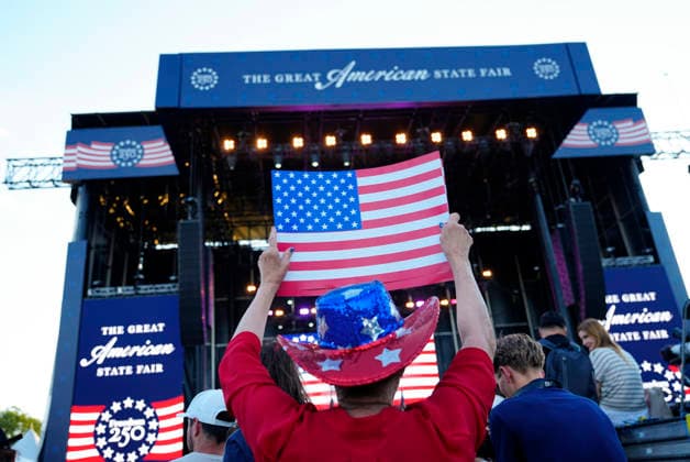 Attendees hold American flags before President Donald Trump speaks at a rally to kick off the 16-day Great American State Fair as part of Washington, D.C. s celebration of the nation s 250th birthday on the National Mall on Wednesday, June 24, 2026. The rally will include military flyovers, musical performances from Lee Greenwood and Christopher Macchio, and the U.S. Army Band, the U.S. Marine Band and Armed Forces choirs.  WAP20260624360 BONNIExCASH