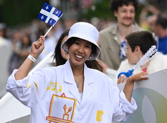 June 24, 2026, Montreal, Pq, Canada: A participant waves a Quebec flag as she entertains the crowd during the Saint-Jean-Baptiste Day parade in Montreal, on Wednesday, June 24, 2026. Montreal Canada  - ZUMAc35_ 20260624_zaf_c35_184 Copyright: xGrahamxHughesx