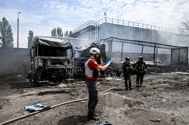 Rescuers and a paramedic work at a parking lot, where a fire broke out due to Russian drone strikes, Zaporizhzhia, Ukraine, June 25, 2026. The Russian army attacked the city with strike drones, targeting a petrol station, Ukrzaliznytsia (Ukrainian Railways) locomotives and a parking lot. Fires broke out, and one person was killed as a result of the attack. (Photo by Dmytro Smolienko Ukrinform) Russia attacks parking lot in Zaporizhzhia with drones  Copyright: xDmytroxSmolienkox