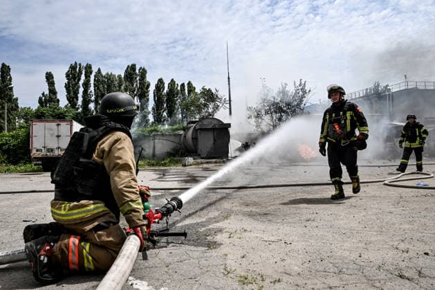 A rescuer pours water to extinguish a fire caused by Russian drone strikes at a parking lot, Zaporizhzhia, Ukraine, June 25, 2026. The Russian army attacked the city with strike drones, targeting a petrol station, Ukrzaliznytsia (Ukrainian Railways) locomotives and a parking lot. Fires broke out, and one person was killed as a result of the attack. (Photo by Dmytro Smolienko Ukrinform) Russia attacks parking lot in Zaporizhzhia with drones  Copyright: xDmytroxSmolienkox