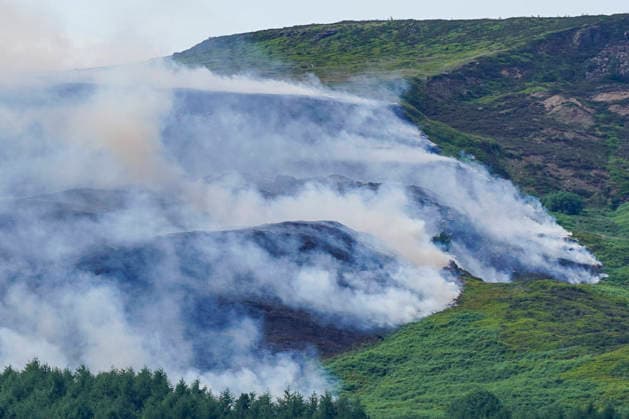 June 25, 2026, Glossop, Derbyshire, UK: Glossop, UK. A helicopter flies above a wildfire as burns near a forest in Glossop near Wood Head Reservoir, Derbyshire. A four-day amber heat and extreme heat warning has been put in place by the Met Office, with temperatures expected to peak by the end of the week. Glossop UK  - ZUMAl94_ 20260625_zaf_l94_045 Copyright: xIoannisxAlexopoulosx