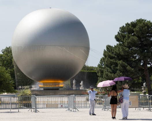 (260625) -- PARIS, June 25, 2026 -- Visitors take photos in front of the Paris 2024 Olympic cauldron near the Louvre Museum amid the heatwave, in Paris, France, June 25, 2026. ) FRANCE-PARIS-HEATWAVE WuxHuiwo 