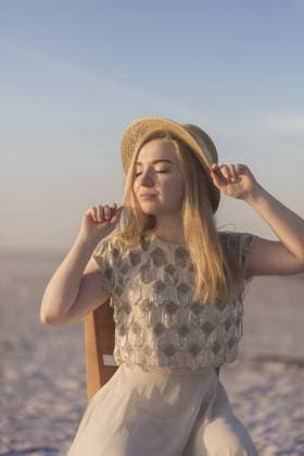 Nahaufnahme eines blonden Mädchens mit einem Strohhalm in der Hand, sie lacht und schaut in die Kamera. Der Hut ist mit Sonnenblumen geschmückt. Sommer, sonniges Wetter Close-up of a blonde girl with a straw has in her hands, she laughs and looks at the camera. The hat is decorated with sunflowers. Summer, sunny weather Copyright: imageBROKER HannaxNikulnikova ibxiqx18087398.jpg ,model released, Symbolfoto ,property released