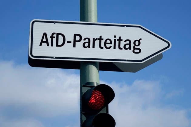 RECORD DATE NOT STATED Fotomontage: Wegweiser zum AfD-Parteitag und rote Ampel, 26.06.2026, Über einer roten Ampel befindet sich ein Wegweiser mit dem Schriftzug AfD-Parteitag. Symbolbild, Symbolfoto, Himmel, blau, Ampel, rot, rote Ampel, Stopp, stoppen, Halt, halten, anhalten, Schild, Pfahl, Wegweiser, Vorwegweiser, Weg, weisen, Pfeil, Pfeilwegweiser, Richtung, Richtungsanzeige, Richtungsangabe, Ziel, Zielangabe, Hinweiszeichen, Schriftzug, Erfurt, Landeshauptstadt Erfurt, AfD-Parteitag, Parteitag, Parteitag der AfD, Bundesparteitag, Delegierte, AfD-Delegierte, Delegiertenversammlung, Parteikonvent, Parteitagsreden, Parteiveranstaltung, Gesamtversammlung, Parteitagsprogramm, Parteitagsbeschlüsse, Parteitagsbeschluesse, Parteitagsproteste, friedliche Proteste,