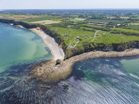 Luftbild der geschichtsträchtigen Landzunge Pointe du Hoc an der Steilküste der Normandie. Die grüne Klippe ragt markant in den blauen Atlantik. Deutlich zu erkennen sind die zahlreichen, tiefen Bombenkrater aus dem Zweiten Weltkrieg, die die Landschaft bis heute prägen. An diesem ehemaligen Stützpunkt der deutschen Wehrmacht fand am 6. Juni 1944 während der alliierten Invasion, D-Day, Operation Overlord eine entscheidende Schlacht statt, Omaha Beach, Département Calvados, Normandie, Ärmelkanal, Frankreich Aerial view of the historic Pointe du Hoc headland on the cliffs of Normandy. The green cliff rises prominently into the blue Atlantic. The numerous, deep bomb craters from the Second World War, which still shape the landscape today, Copyright: imageBROKER MarkusxKeller ibxmkl18101343.jpg
