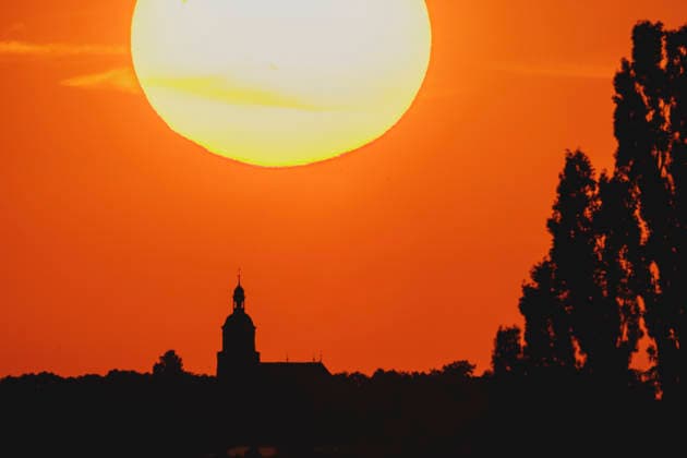 Eine Kirche zeichnet sich ab vor der untergehenden Sonne in Malschwitz, 26.06.2026. Deutschland durchlebt eine grosse Hitzewelle mit teils ueber 40 Grad. Malschwitz Deutschland *** A church is silhouetted against the setting sun in Malschwitz, June 26, 2026. Germany is experiencing a major heat wave, with temperatures in some areas exceeding 40 degrees. Malschwitz, Germany Copyright: xFlorianxGaertnerx