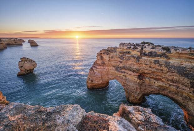 Sonnenaufgang am Strand Praia da Marinha an der Algarve, Portugal, mit Klippen, Seestapeln und ruhiger Morgenküste Sunrise at Praia da Marinha beach in Algarve, Portugal, with ocean cliffs, sea stacks and quiet morning shoreline Copyright: imageBROKER DmitryxRukhlenko ibxdmr18172734.jpg
